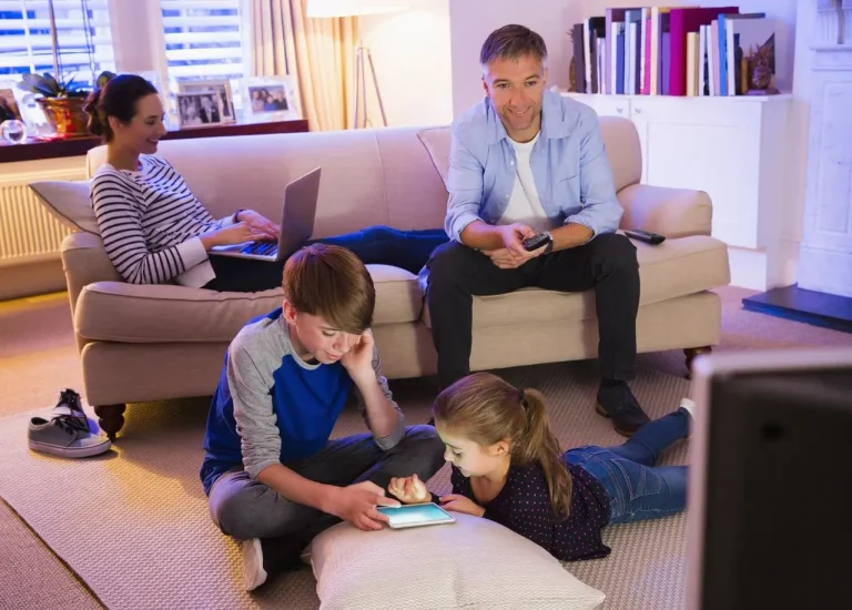 Child using a device in a shared family room with parental supervision
