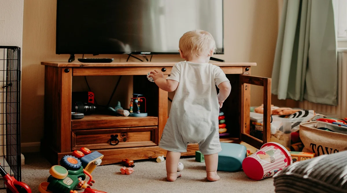Child near toys and a tablet in a family room during screen time decision-making