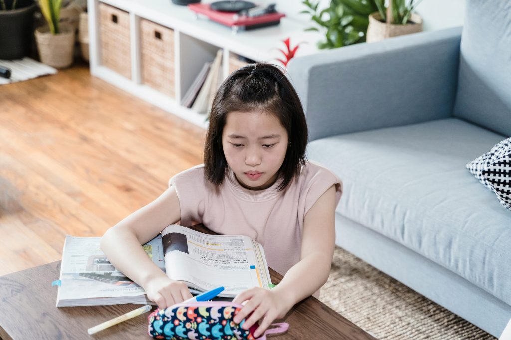 Child transitioning into a home learning activity with books and materials ready