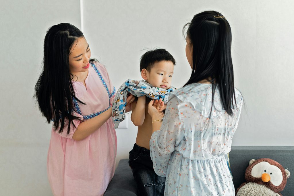Child practicing a dressing skill with a parent nearby