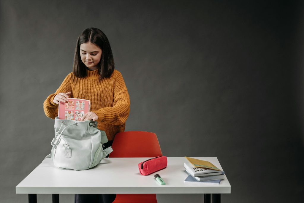 Child putting completed homework into a school bag