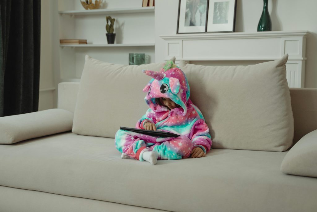 Tired child sitting on a sofa near a tablet at home