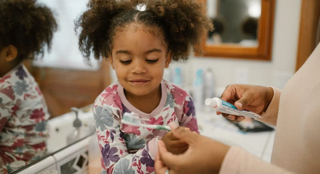 Parent calmly inviting a child into a prepared toothbrushing routine at home