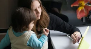 Parent and child placing a tablet on its regular charger after screen time