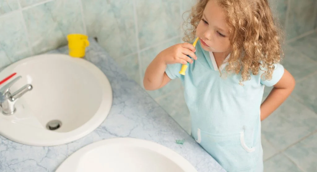 Child walking into a bathroom with the sink already running for toothbrushing