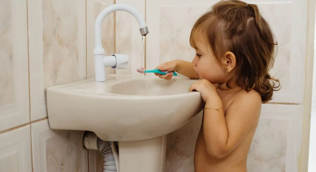Toothbrush and running sink prepared for a child’s bedtime brushing routine