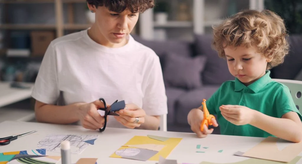 Parent adding one new craft supply after a child finishes the previous step