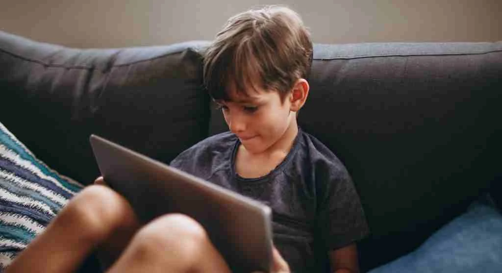 Child looking at a tablet home screen before handing over the device