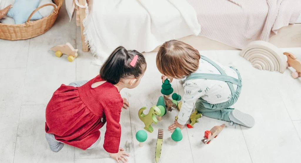 Children learning to take turns during play while a parent stays nearby
