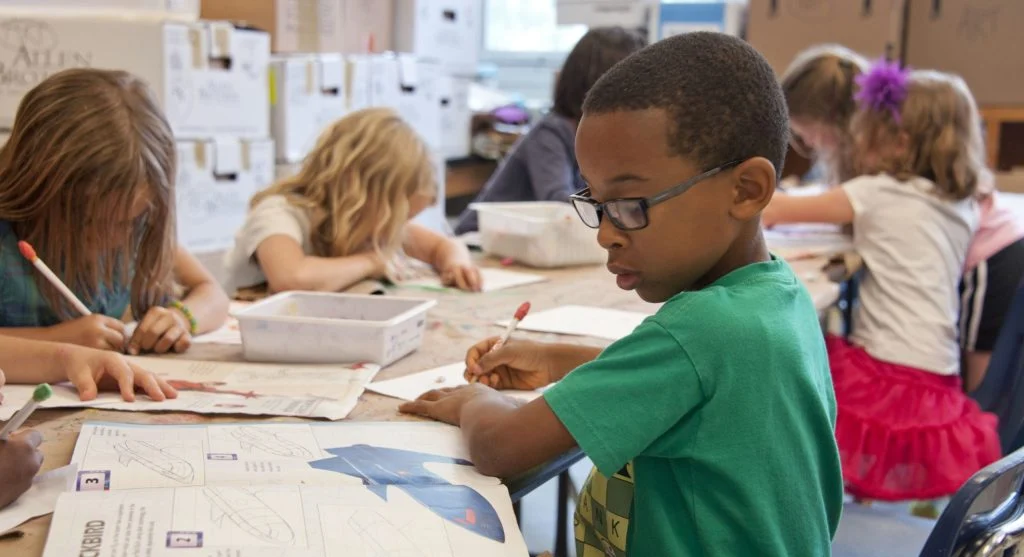 Child circling the key action word in worksheet directions at a table