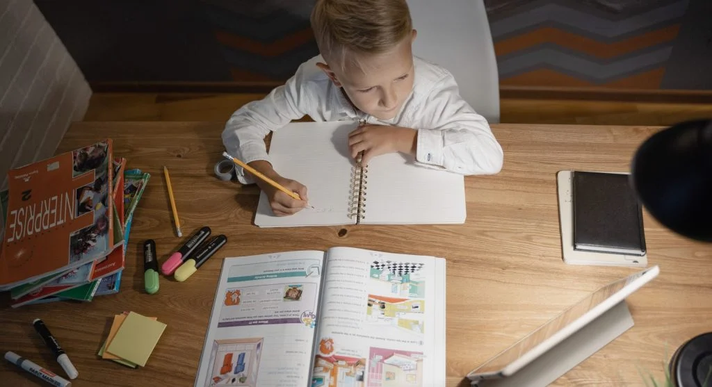 Child pointing to a sentence in a book before answering a reading question at home