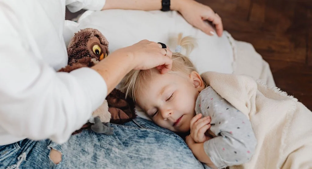 Child leaning on a familiar comfort habit while staying close to a parent