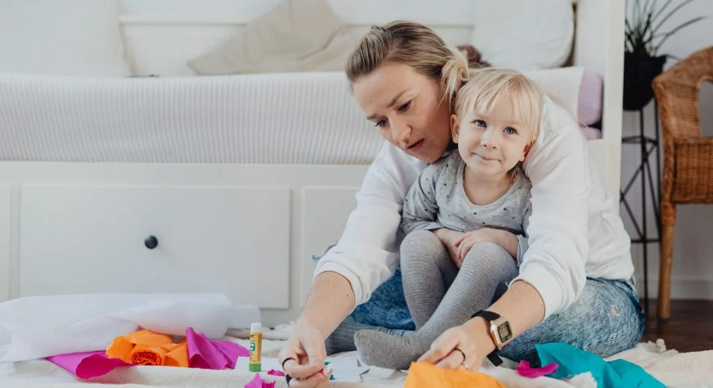 Calm parent guiding a step-by-step craft with limited supplies visible