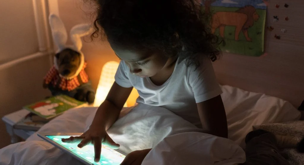 Child putting a tablet in its regular resting place after screen use at home