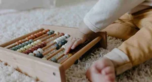 Parent helping a child count objects by sliding each one into a new space at home
