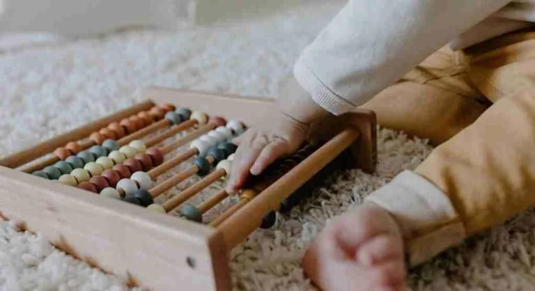 Parent helping a child count objects by sliding each one into a new space at home