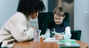 Parent helping a child begin writing practice with a starter line on paper