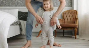 Parent setting out the first clothing item to help a child get dressed at home
