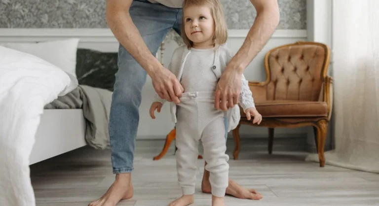 Parent setting out the first clothing item to help a child get dressed at home