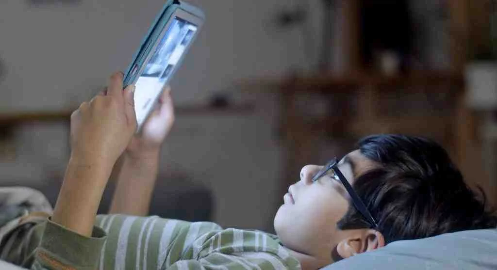 Child looking at a device resting place before handing over a tablet