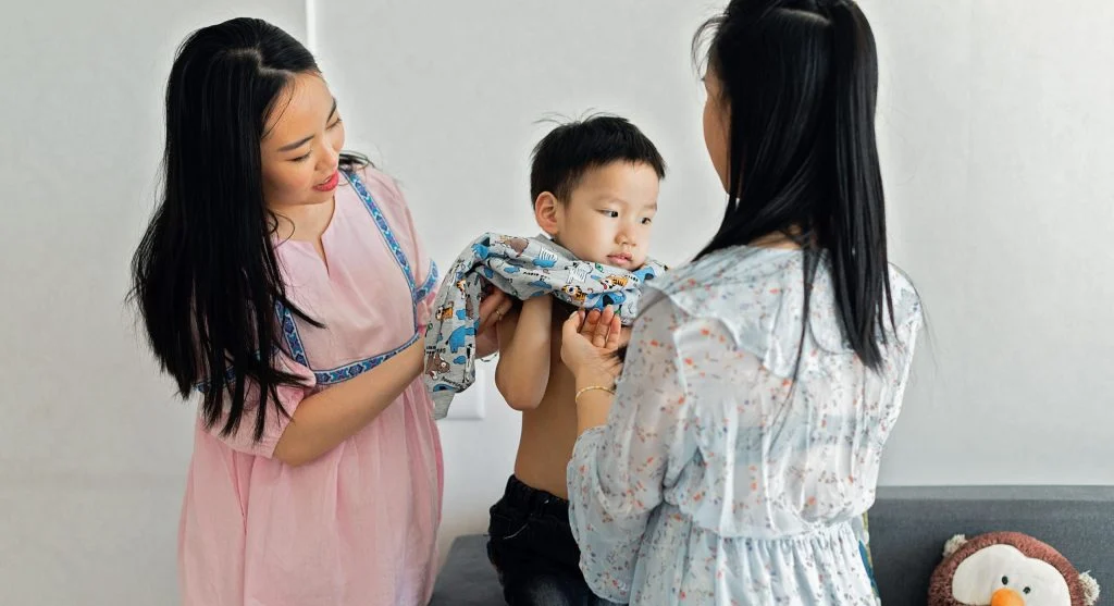 Parent handing a child the first clothing item to start the dressing routine