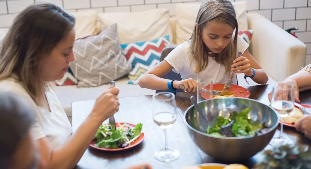 Parent setting out a device basket before serving dinner at home