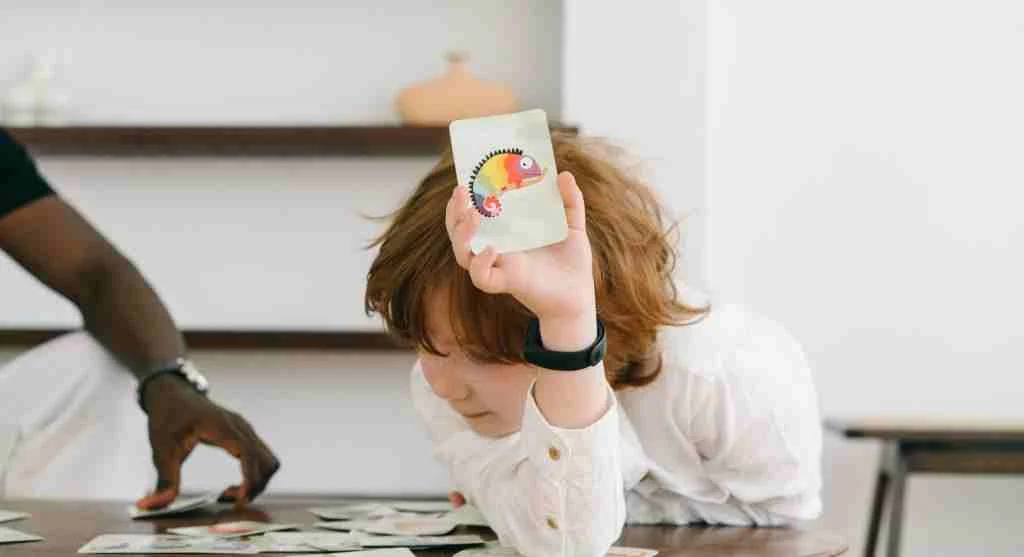 Child looking at picture cards arranged in one row during a beginning sounds activity