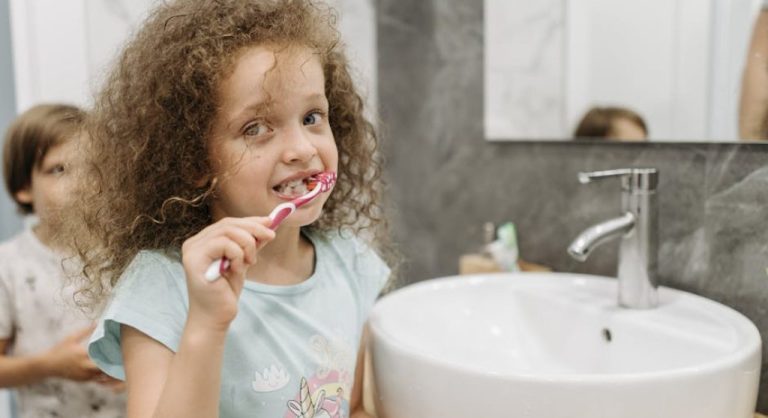 happy kid brushing teeth in bathroom