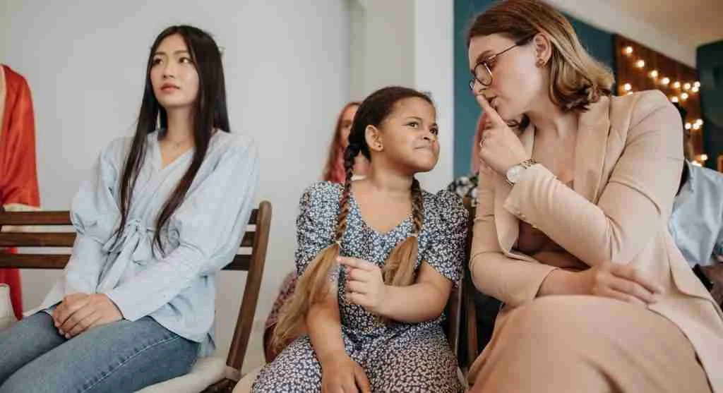 Child trying to whisper something private to a parent in public