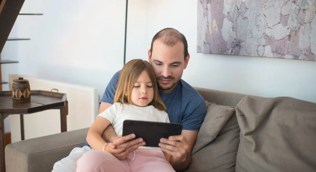 Parent and child putting a device in its usual resting place after screen time at home