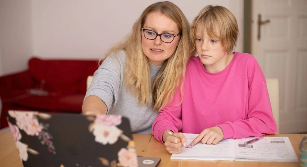 Parent and child pausing to circle the key worksheet instruction before starting